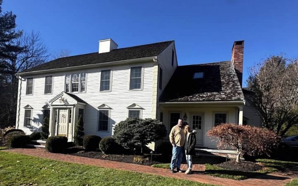 Buyers standing in front of the Norwell, Massachusetts colonial home they purchased with The Market