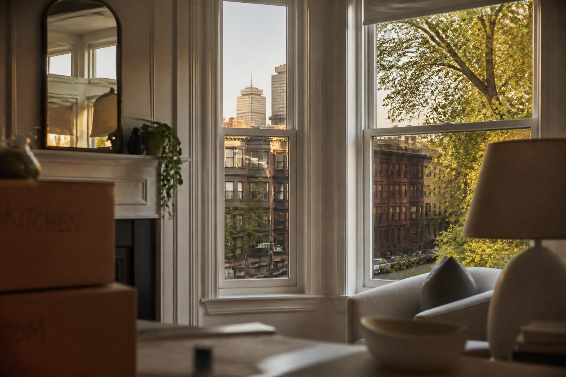Sunlit Boston-area home interior with moving boxes and a view of the city